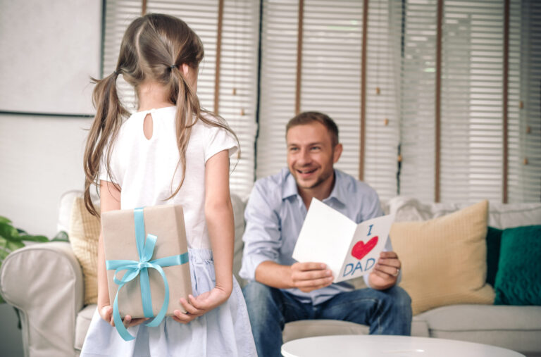 Little girl giving father a card and gift, lifestyle moment