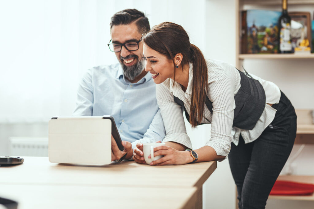 Man and woman looking at tablet device, strategizing online search methods