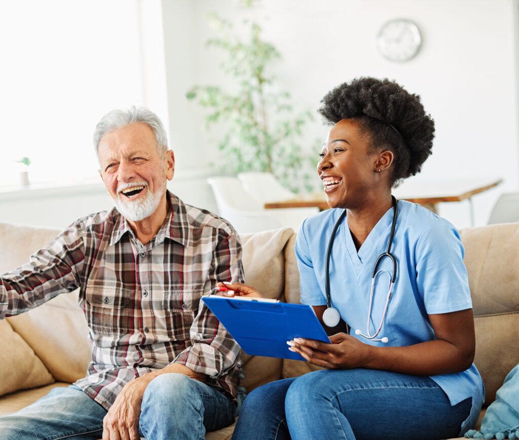 Nurse and senior patient smiling together in home care setting, clipboard in hand