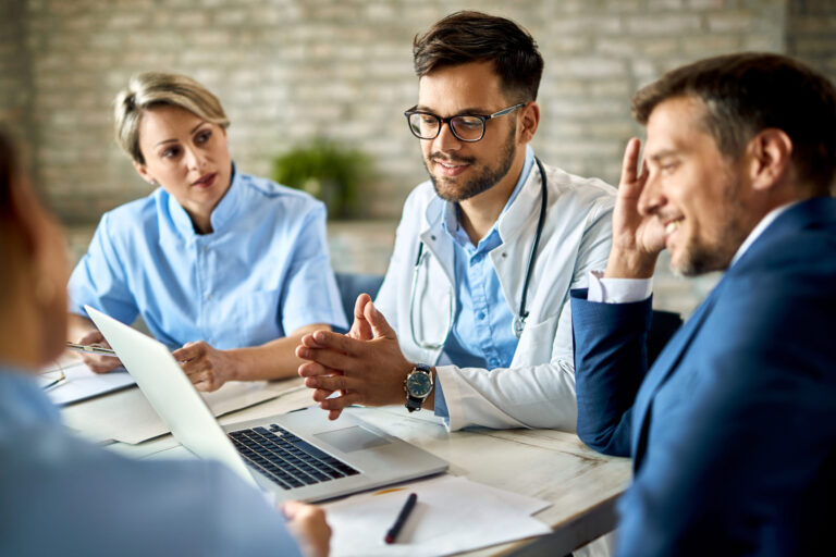 Doctors and businessman collaborating with computer, healthcare administration discussion