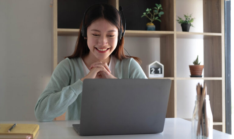 Asian student studying with laptop and headphones, technology and lifestyle insights.