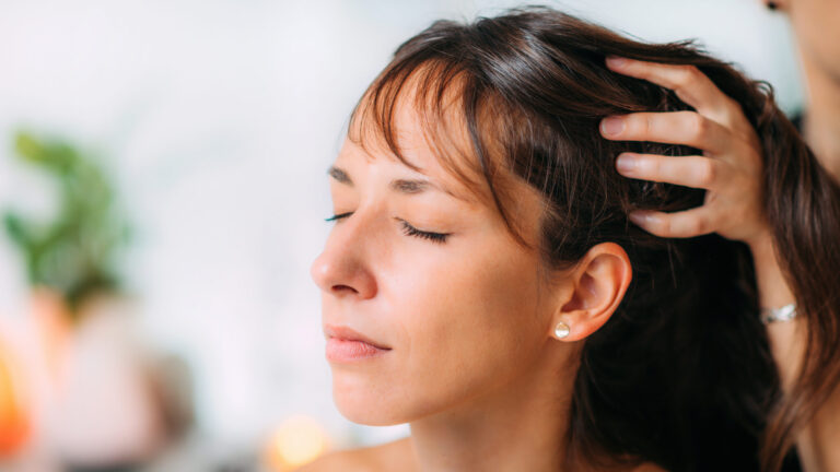Woman receiving Ayurvedic oil hair treatment for personal wellness.