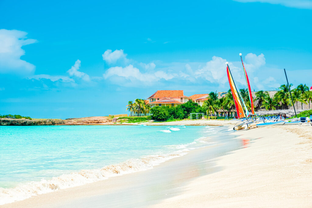Idyllic tropical beach vacation scene with sailboats and turquoise water
