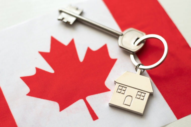 Canadian flag and house key symbolizing immigration and real estate in Canada.