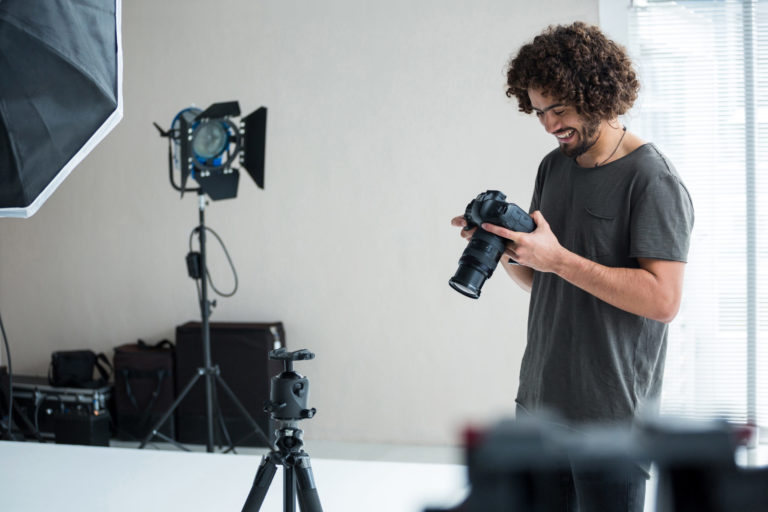 Photographer reviewing photos in studio setting, professional photography equipment.