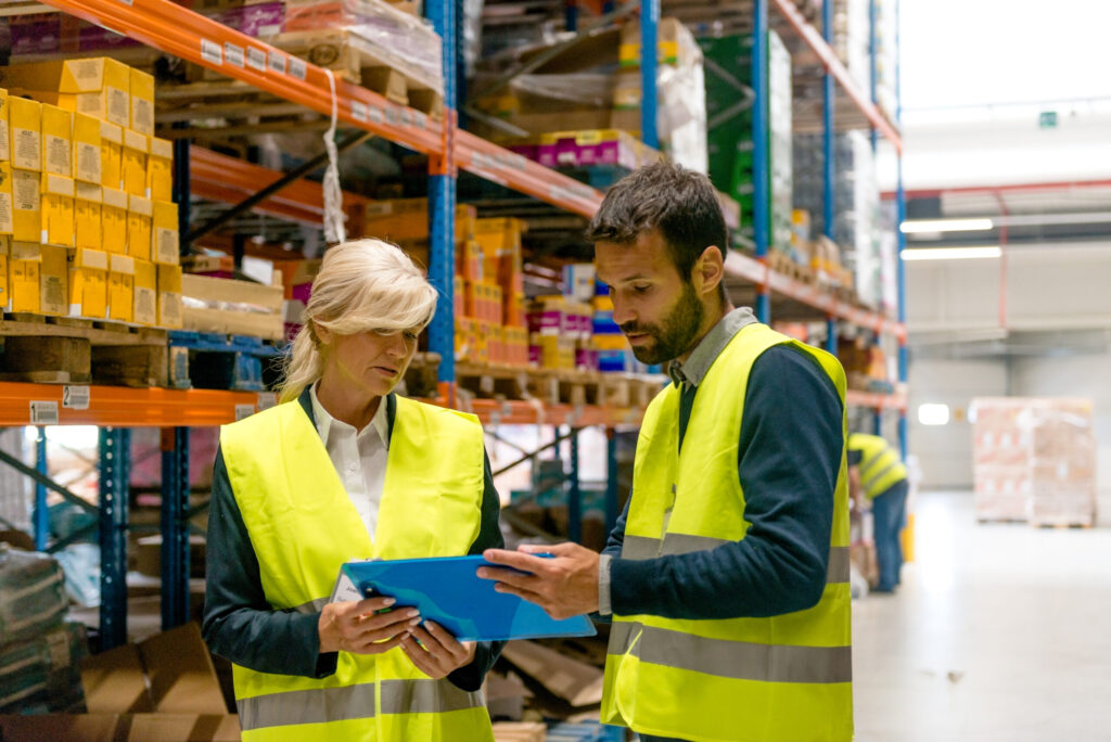 Warehouse staff reviewing equipment inventory list.