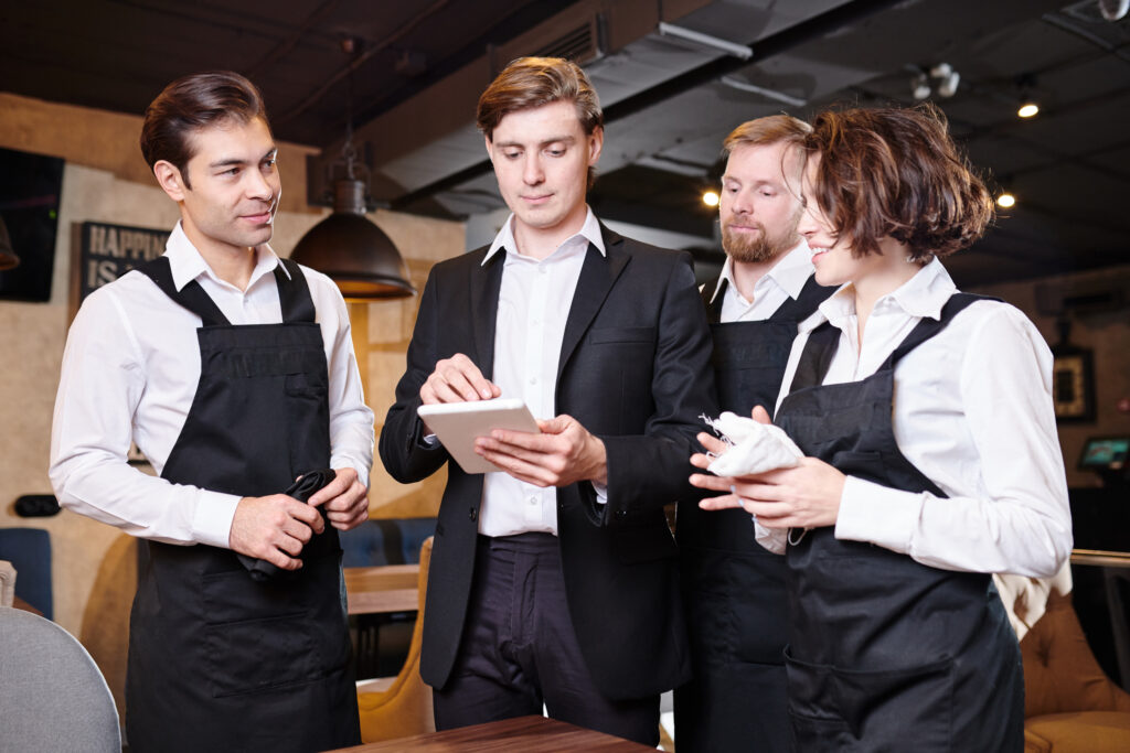 Restaurant manager reviewing responsibilities with staff and restaurant employees.